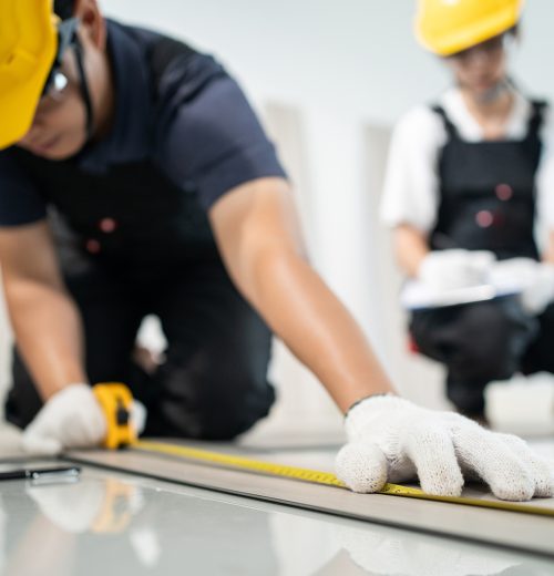 亚洲工匠工人们在家里地板上安装层压板。有吸引力的木匠和木匠检查和计数拼花地板，帮助建筑工人修复走廊，装修公寓或房子。